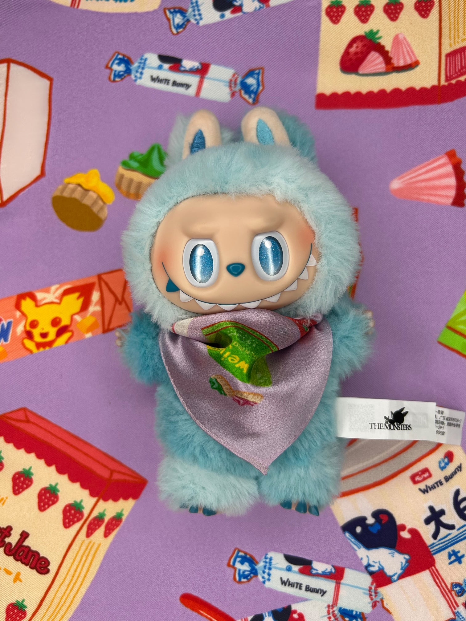 Plush toy labubu with a bandana surrounded by colorful packaging on a purple background